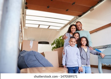 Portrait Of Family Standing On Tailgate Of Removal Truck Outside New Home