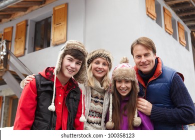 Portrait Of Family Standing Outside Chalet On Ski Holiday