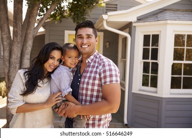 Portrait Of Family Standing Outside Home