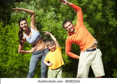 Portrait Of Family Of Three Doing Physical Exercise In Park