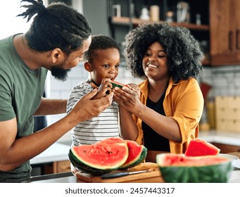 Portrait of family of three, father, mother and son cutting a watermelon fruit and having fun in the kitchen at home, healthy food and family bonding concepts - Powered by Shutterstock