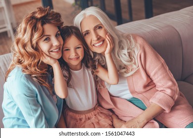 portrait of family of three generations sitting on the sofa and looking at the camera