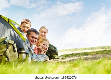 Portrait of family of travelers in tent looking at camera - Powered by Shutterstock