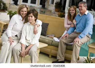 Portrait Of Family With Two Children Sitting On Patio