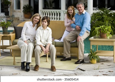 Portrait Of Family With Two Children Sitting On Patio