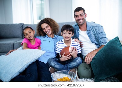 Portrait Of Family Watching American Football Match On Television At Home