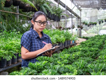 Portrait of a farmer Asian woman at work in greenhouse with notebook examines the growing seedlings on the farm and diseases in greenhouse. - Shutterstock ID 1489574903