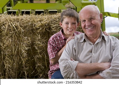 Portrait Of Farmer And Grandson On Tractor With Straw