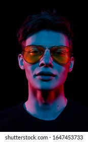 Portrait Of A Fashion Trend Male Model Neon Gel Light In Studio On A Dark Black Background