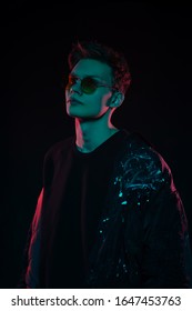 Portrait Of A Fashion Trend Male Model Neon Gel Light In Studio On A Dark Black Background