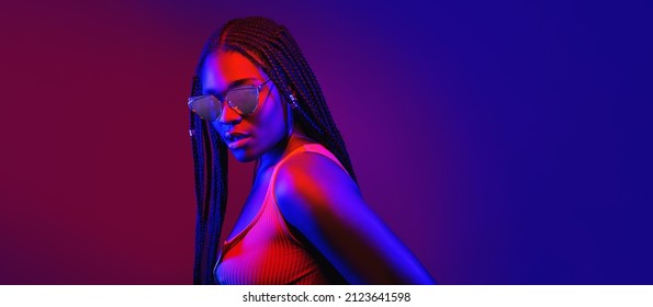 Portrait Of Fashion Young Girl In Cool Sunglasses In Red And Blue Neon Light In The Studio