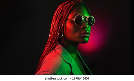 Portrait Of Fashion Young Girl In Round Sunglasses In Red And Green Neon Light In The Studio