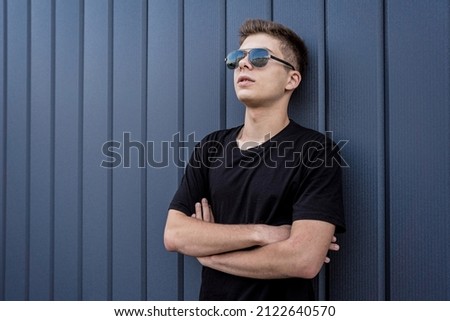Portrait of a fashion young man leaning against a blue wall