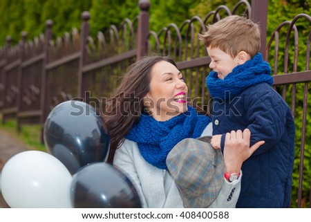 Portrait of fashionable baby boy and his gorgeous mother among balloons. little boy hugs his mother emotionally.