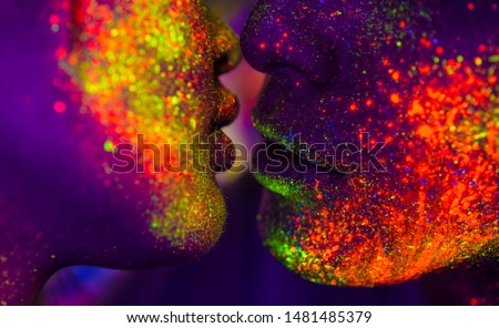Portrait of fashionable couple  with colored fluo painting on the face - Fashion models on colored background