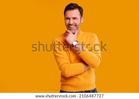 Portrait of fashionable handsome man posing on the yellow studio background, smiling. Casual fashion for men. A lot of copy space.   