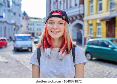 Portrait Of Fashionable Hipster Teenage Girl With Colored Dyed Hair In Black Cap And Headphones, City Street Background. Lifestyle, Fashion, Trends, Youth Concept