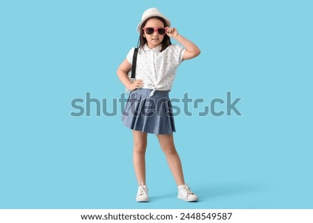 Portrait of fashionable little girl with sunglasses on blue background