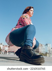 Portrait Of Fashionable Young Woman In Casual Clothes Crouching Outdoors, With The Sky Behind Her, Vertical Image For Social Media