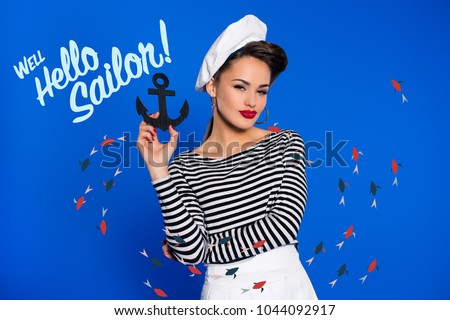 portrait of fashionable young woman in retro clothing with anchor in hand and well hello sailor inscription isolated on blue