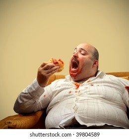 portrait of fat man eating hamburger seated on armchair