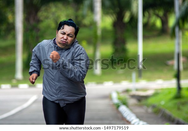 公園でジョギングするのに疲れを感じる太った男性のポートレート 彼は痩せて 完璧な体を手に入れる必要がある の写真素材 今すぐ編集