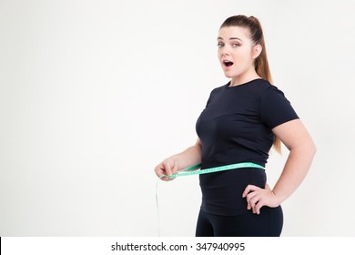Portrait of a fat woman measuring her waist and looking at camera isolated on a white background