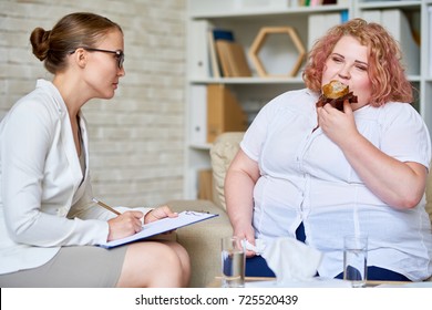 Portrait of fat young woman  eating cupcakes during therapy session with female psychiatrist