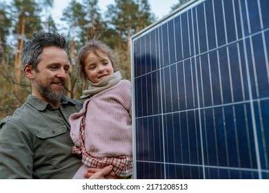 Portrait of father and daughter holding a solar panel in garden. - Powered by Shutterstock