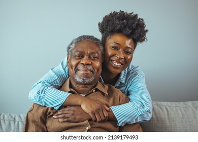 Portrait of father and daughter laughing and being happy.  Daughter with her arm around her father both smiling. Smiling young woman enjoying talking to happy old father. 
