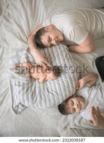 Similar – Mother reading book to her sons in the bed