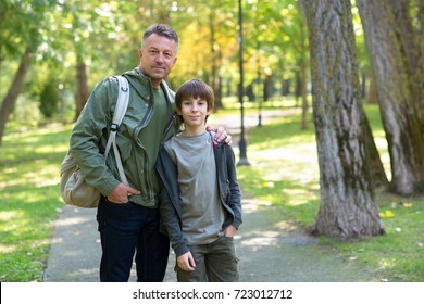 Portrait of father with his son walking together in autumn park. Family leisure. Parenting. Parenthood.