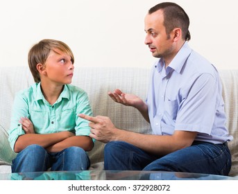 Portrait Of Father And His Teenager Son Having Serious Conversation Indoors
