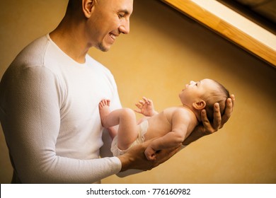 Portrait Of Father Holding Newborn Baby At Home near window