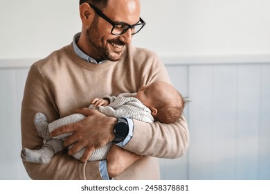 Portrait of a father hugging and kissing newborn baby. Authentic lifestyle touching tender moment. - Powered by Shutterstock