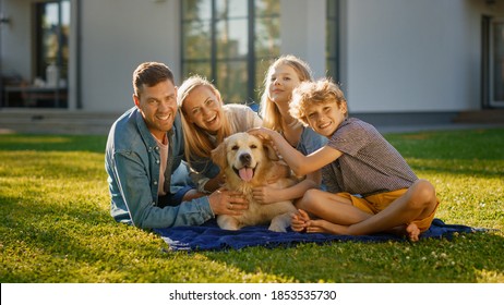 Portrait Of Father, Mother And Son Having Picnic On The Lawn, Posing With Happy Golden Retriever Dog. Idyllic Family Have Fun With Loyal Pedigree Dog Outdoors In Summer House Backyard.
