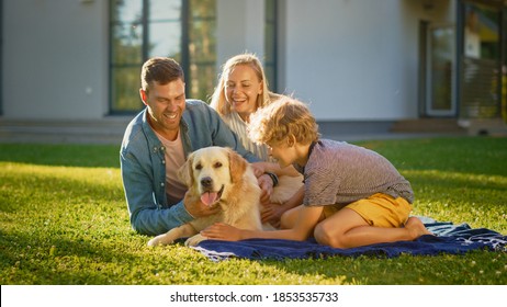 Portrait of Father, Mother, and Son Having Picnic on the Lawn, Posing with Happy Golden Retriever Dog. Idyllic Family Have Fun with Loyal Pedigree Doggy Outdoors in Summer House Backyard. - Shutterstock ID 1853535733