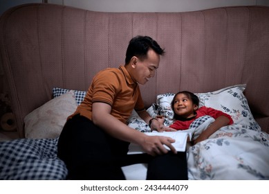 Portrait father read the bedtime story to his daughter lying on the bed. Family activity concept