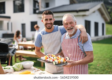 Portrait Of Father And Son Outdoors On Garden Barbecue, Grilling.