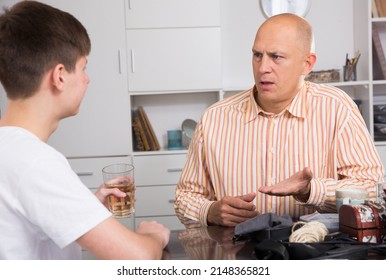 Portrait Of Father Talking To Teenage Son, Having Friendly Conversation At Home