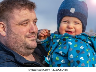 portrait of a father who, smiling, looks lovingly at his little son, holding him in his arms.