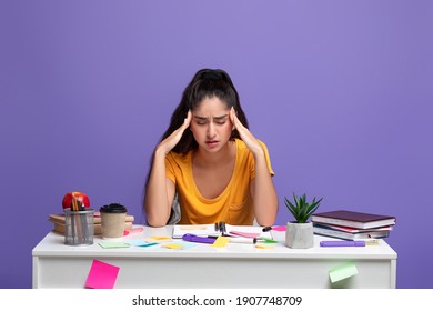 Portrait Of Fatigue Tired Indian Lady Feeling Headache Or Stress, Touching And Massaging Her Temples, Trying To Learn And Study, Sitting At Desk With Notebook. Woman Doing Homework And Thinking