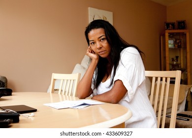 Portrait Of Fed Up Mature Woman Sitting At Dining Table Reading Bill