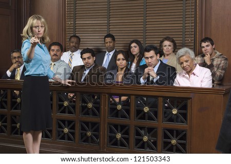 Portrait of a female advocate pointing with jurors sitting together in the witness stand at court house