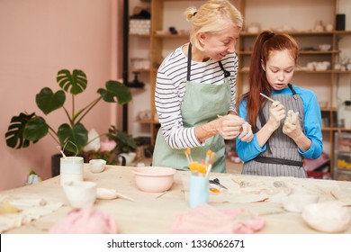 Portrait of female art teacher helping teenage girl create handmade ceramics in pottery class, copy space - Powered by Shutterstock