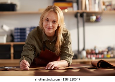 Portrait of female artisan smiling at camera while working with leather in workshop, copy space - Powered by Shutterstock