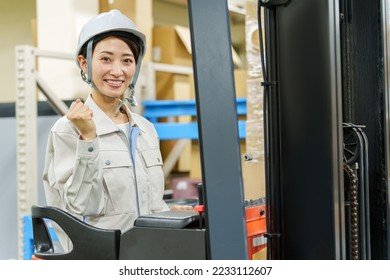 portrait of female asian worker driving forklift in warehouse - Shutterstock ID 2233112607
