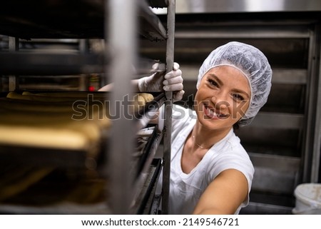 Portrait of female baker in white clean uniform and hairnet preparing bread in bakery production.