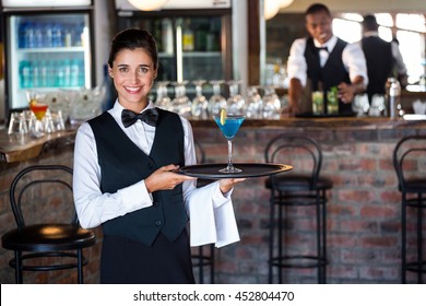 Portrait Of Female Bartender Holding Serving Tray With Glass Of Cocktail