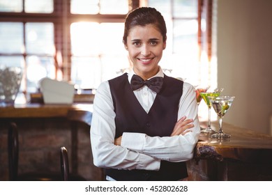Portrait of female bartender standing with arms crossed